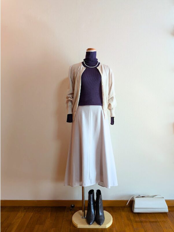 パープルタートルニットにホワイトフレアスカート、ライトベージュカーディガンを合わせたコーデ