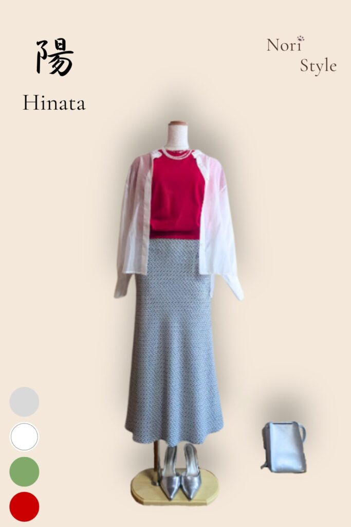 レッドのニットにグリーンのマーメードスカートを合わせ、ホワイトのシアーブラウスを肩に掛けた春夏コーデ。足元とバッグはシルバーで統一し、鮮やかさと上品さが共存する大人のスタイル。