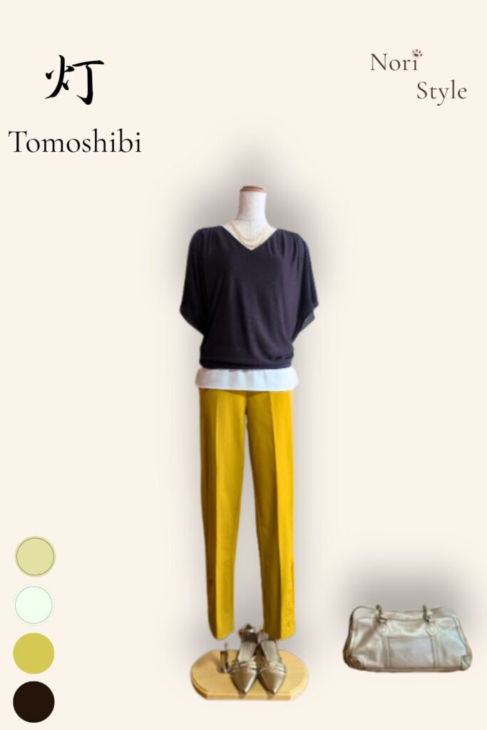 縦長の白を基調とした背景に、トルソーを配した「灯 — Tomoshibi」のコーディネートカード。深みのあるダークブラウンのトップスに、パキッと映えるマスタードイエローのセンタープレスパンツを穿かせた、世界一流ブランドのロジックを取り入れたリラックス・ハンサムスタイルです。左上には「灯 — Tomoshibi」、右上には「Nori Style」、左下にはカラー丸ドット(ダークブラウン、白、マスタード、ベージュ)、右下にはライトゴールドのバッグが配されている。