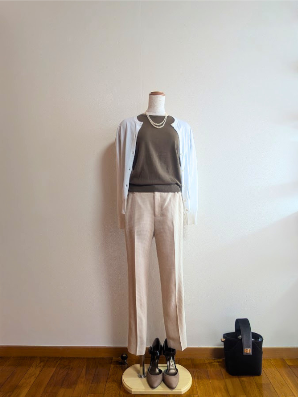 カーキトップスと淡いオレンジベージュのパンツ、白カーディガンのコーデ